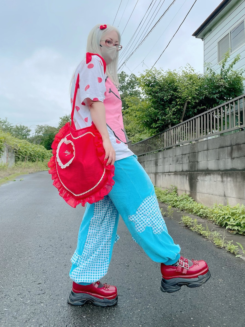 レッド系のショルダーバッグ、レッド系のスニーカー、ピンク系のトップスを着用したレディースの夏コーディネートの4枚目の写真