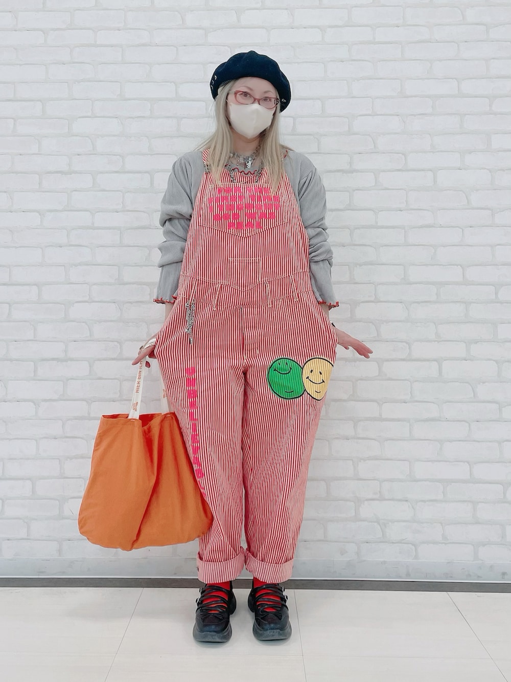 グレー系のTシャツ/カットソー、ピンク系のオールインワン・サロペット、オレンジ系のバッグを着用したレディースの冬コーディネートの2枚目の写真