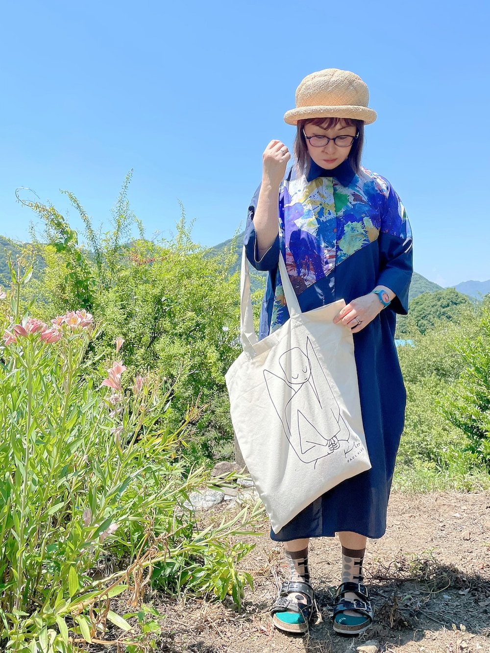 ブルー系のシャツワンピース、ホワイト系のトートバッグ、ブラック系のサンダルを着用したレディースの夏コーディネートの2枚目の写真