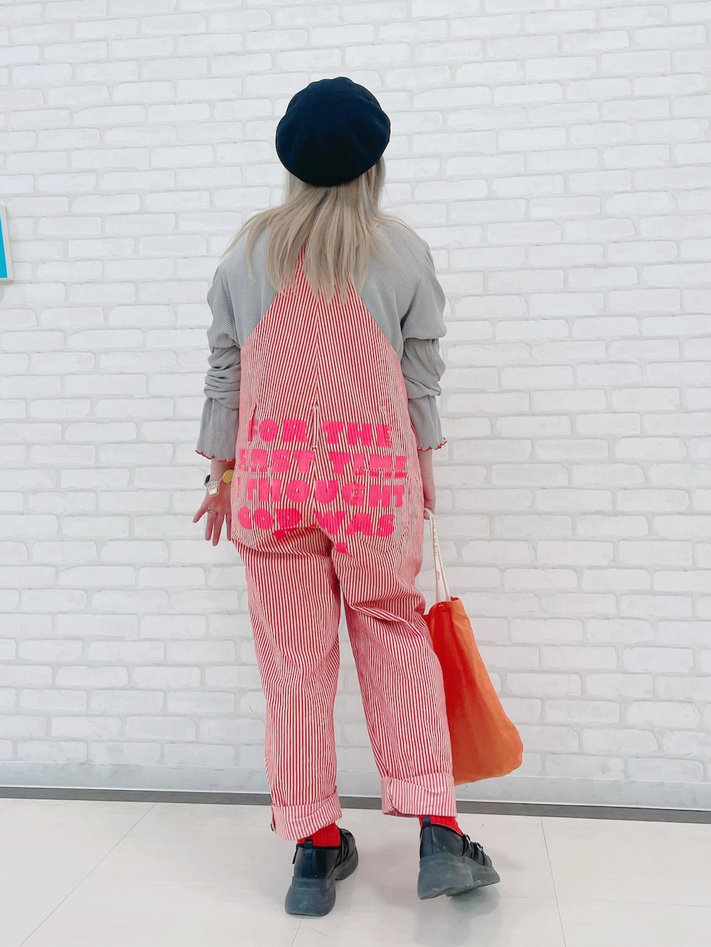 グレー系のTシャツ/カットソー、ピンク系のオールインワン・サロペット、オレンジ系のバッグを着用したレディースの冬コーディネートの3枚目の写真