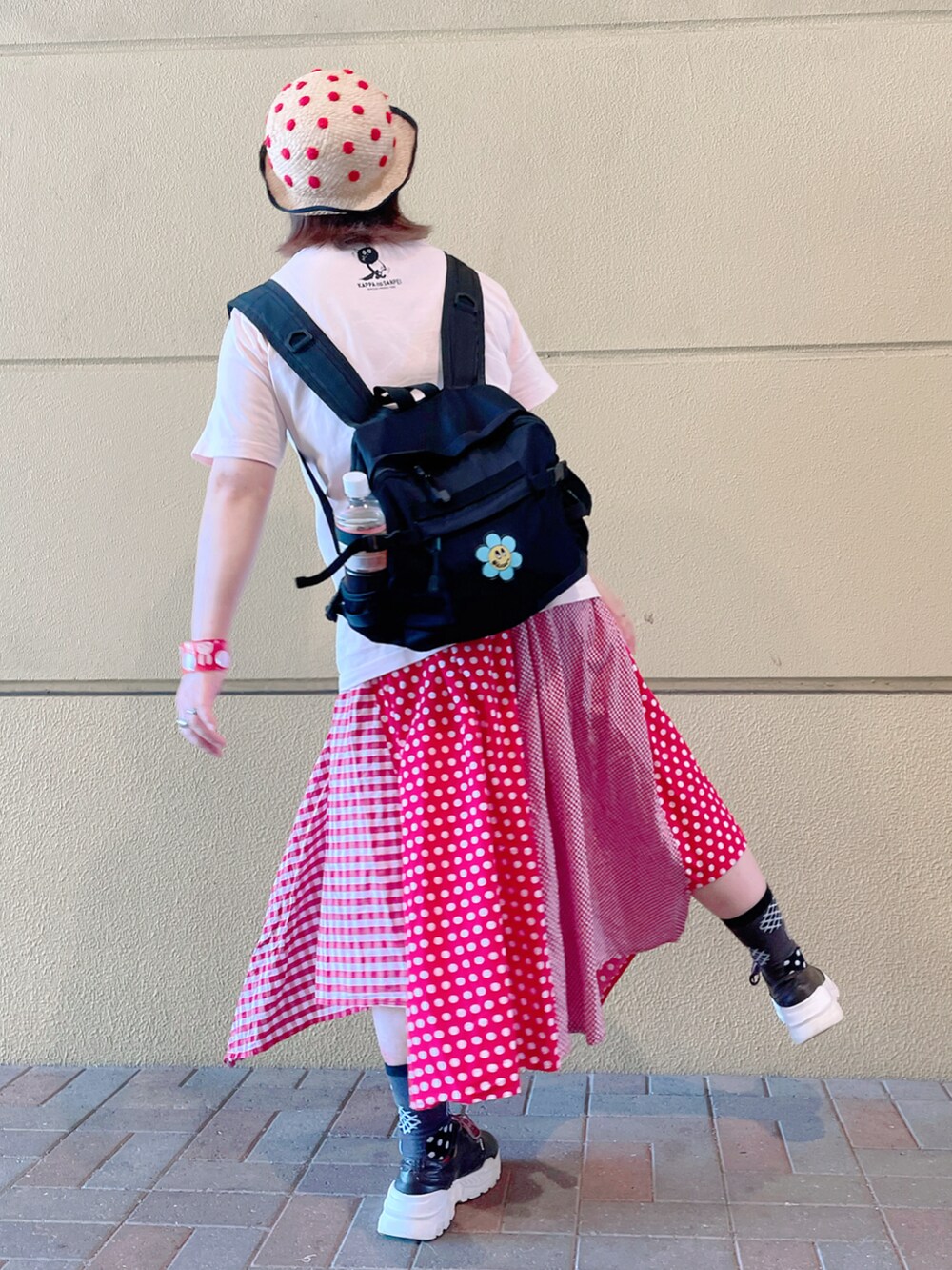ピンク系のトップス、ブラック系のバックパック/リュック、レッド系のスカートを着用したレディースの秋コーディネートの2枚目の写真