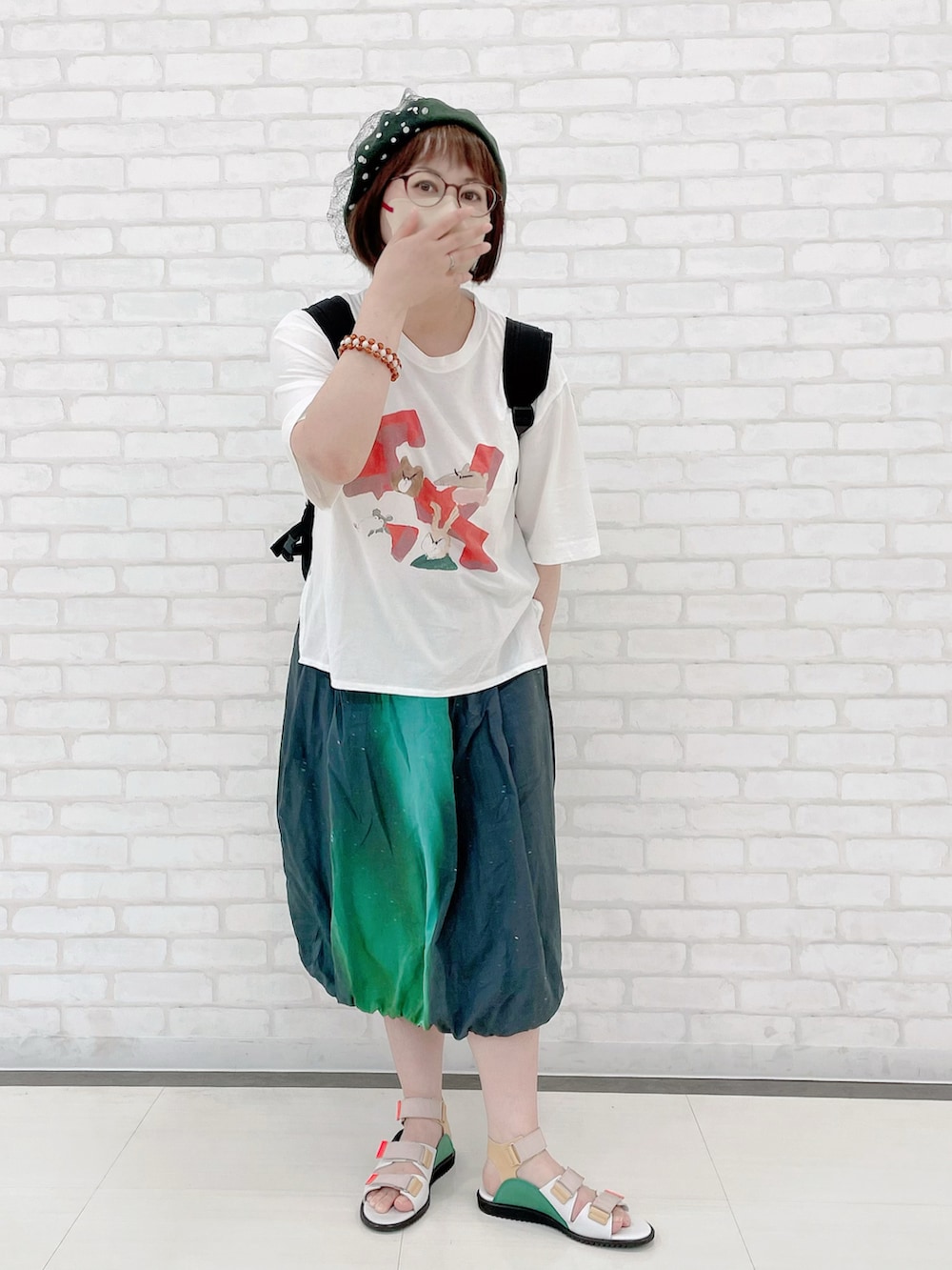 ブラック系のバックパック/リュック、ホワイト系のTシャツ/カットソー、ブラック系のスカートを着用したレディースの夏コーディネートの2枚目の写真