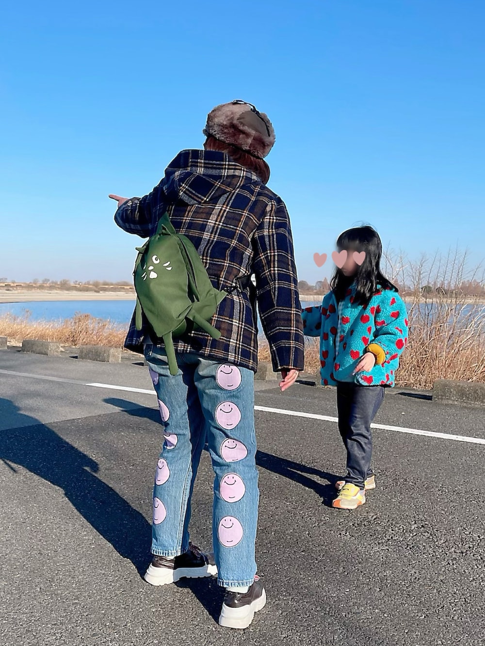 オレンジ系のその他アウター、グリーン系のボディバッグ/ウエストポーチ、ブルー系のデニムパンツを着用したレディースの冬コーディネートの2枚目の写真