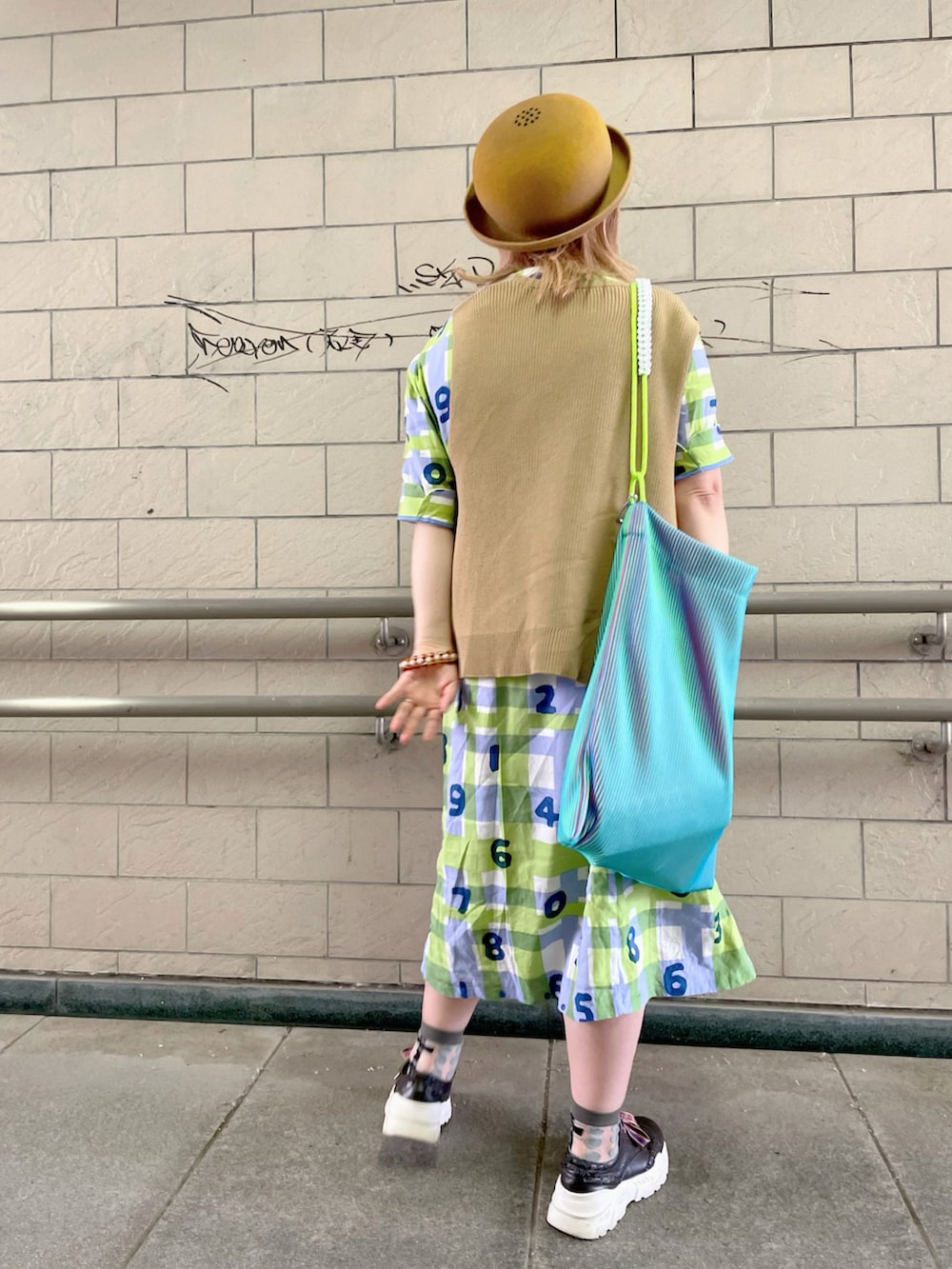 ベージュ系のベスト、ブルー系のトートバッグ、グリーン系のワンピース/ドレスを着用したレディースの春コーディネートの2枚目の写真