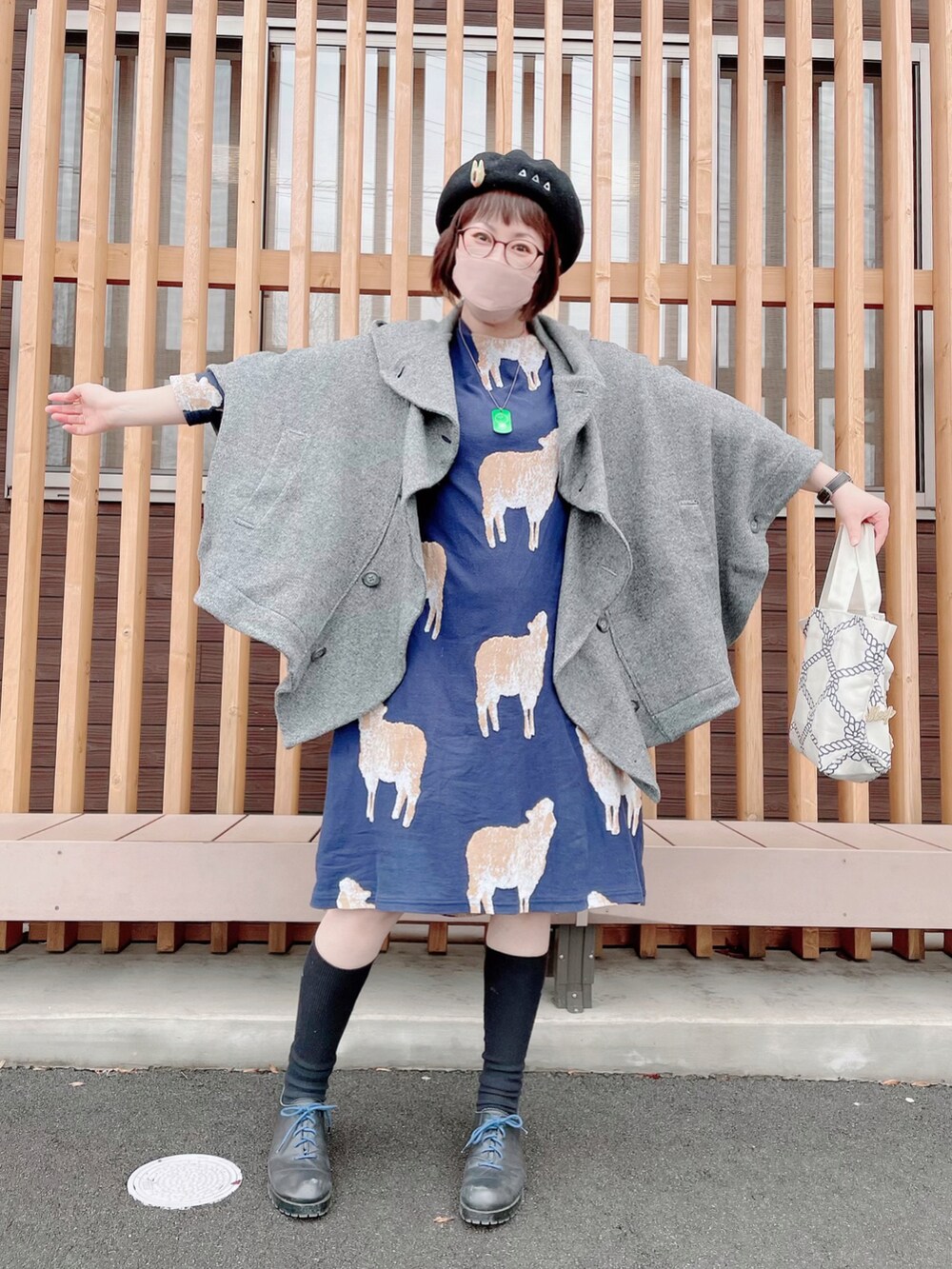 グレー系のポンチョ、ブルー系のワンピース、ベージュ系のトートバッグを着用したレディースの冬コーディネートの2枚目の写真