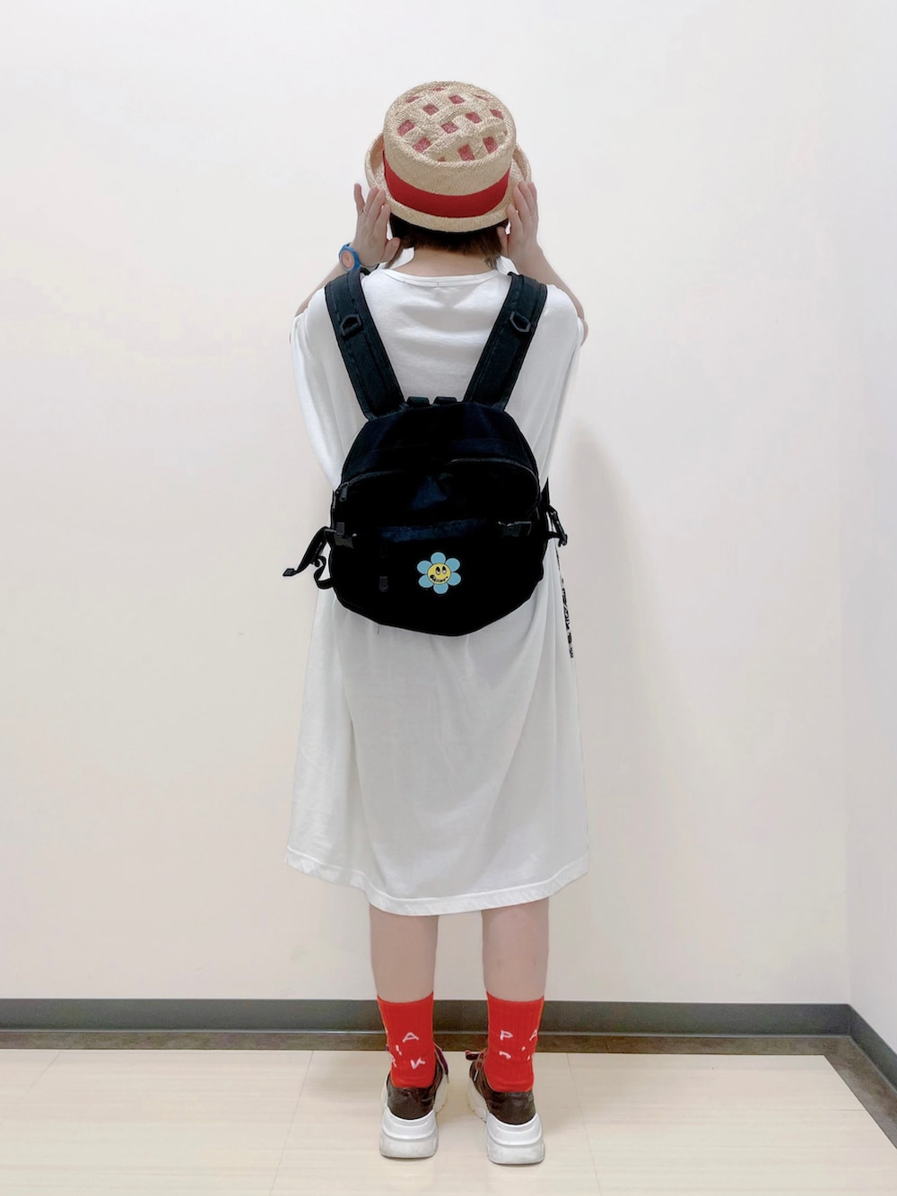 ブラック系のバックパック/リュック、ホワイト系のワンピース、ブラウン系のスニーカーを着用したレディースの夏コーディネートの4枚目の写真