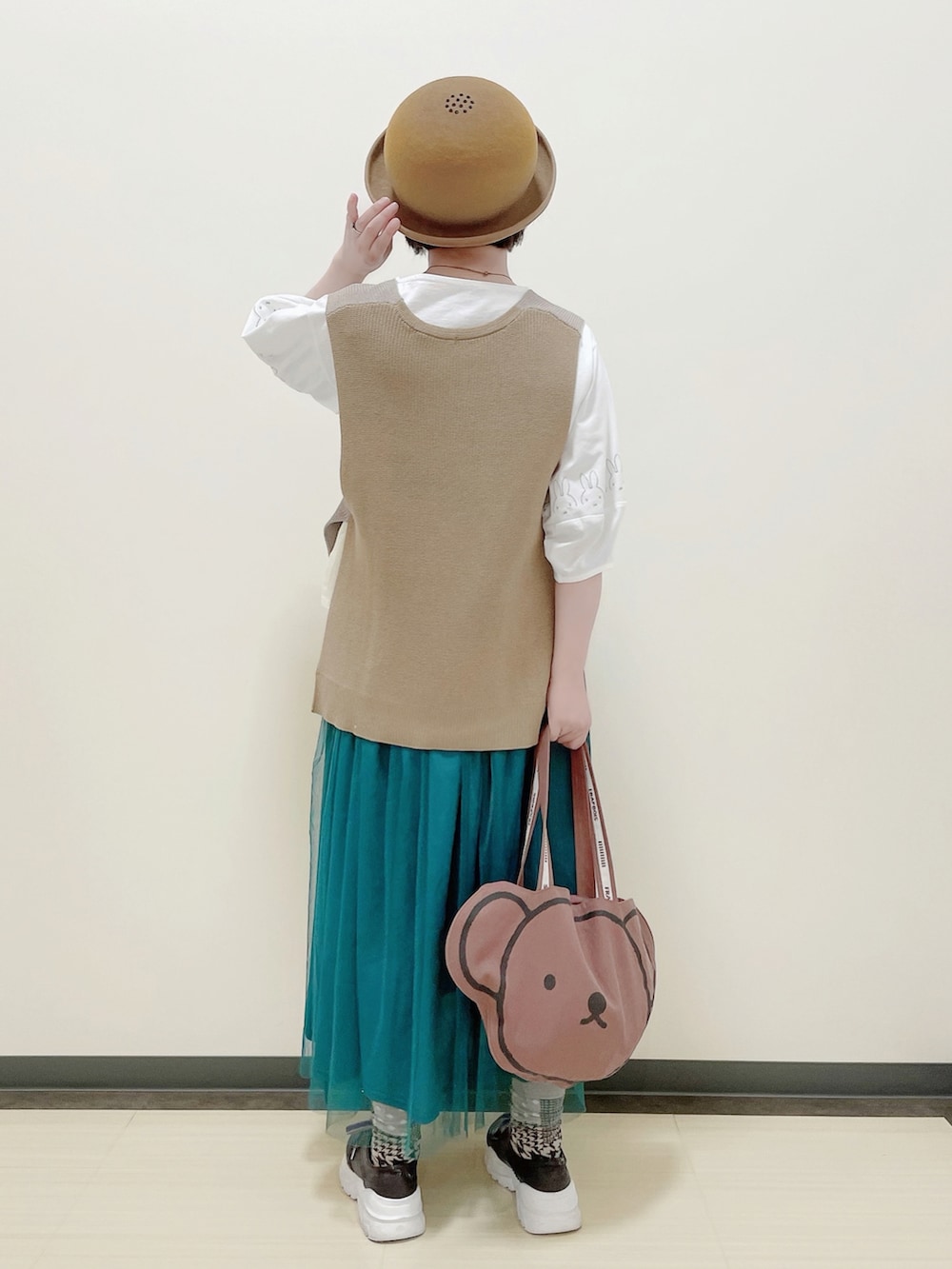 ホワイト系のトップス、ベージュ系のベスト、ブルー系のスカートを着用したレディースの秋コーディネートの2枚目の写真