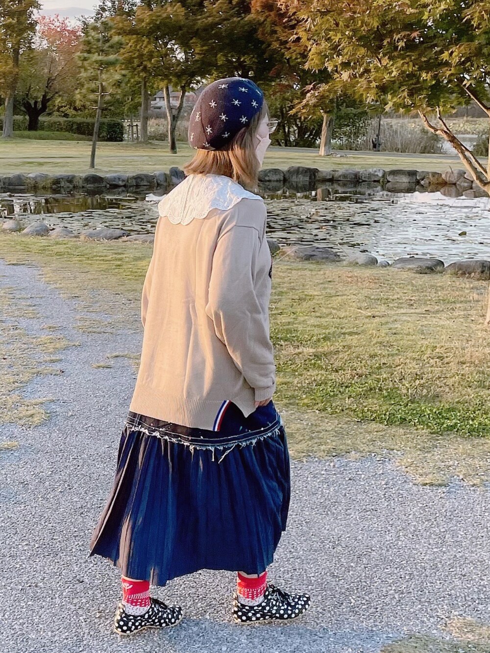 ベージュ系のニット/セーター、ブルー系のショルダーバッグ、ブルー系のスカートを着用したレディースの秋コーディネートの3枚目の写真