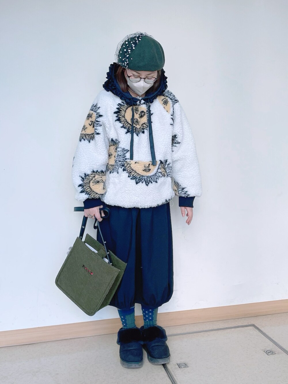 ホワイト系のトップス、グリーン系のショルダーバッグ、ブラック系のスカートを着用したレディースの冬コーディネートの2枚目の写真