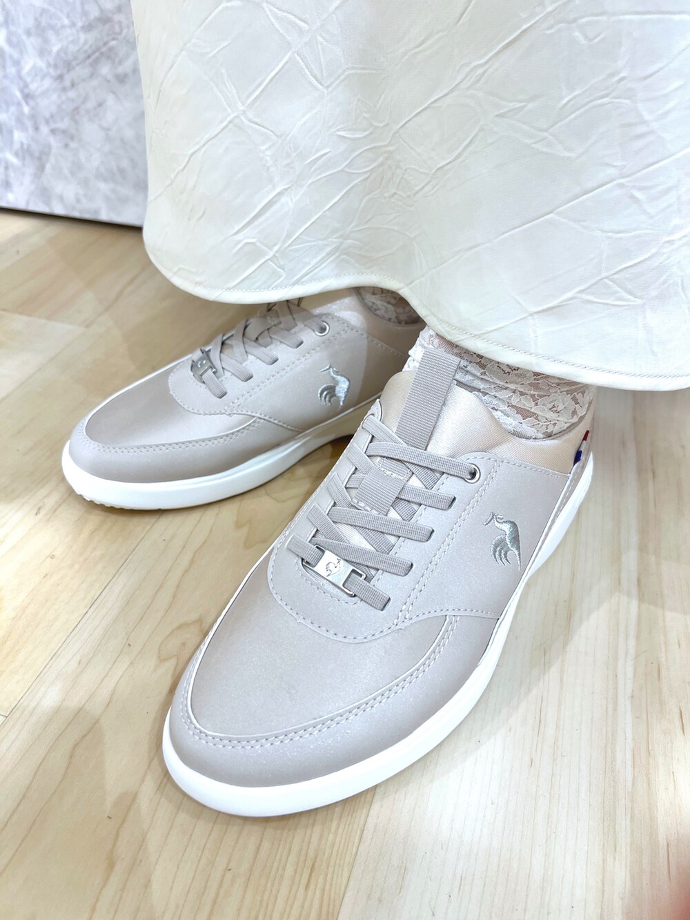 グレー系のスニーカー、ホワイト系のスカート、ベージュ系のトレンチコートを着用したレディースの春コーディネートの6枚目の写真