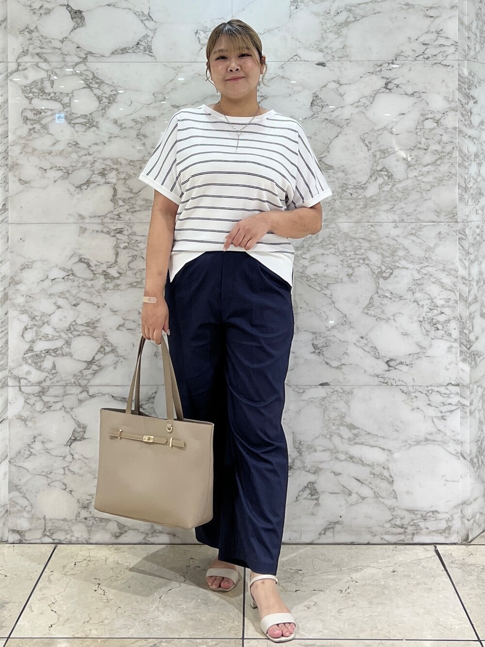ホワイト系のニット/セーター、ブルー系のその他パンツ、ベージュ系のトートバッグを着用したレディースの夏コーディネートの2枚目の写真