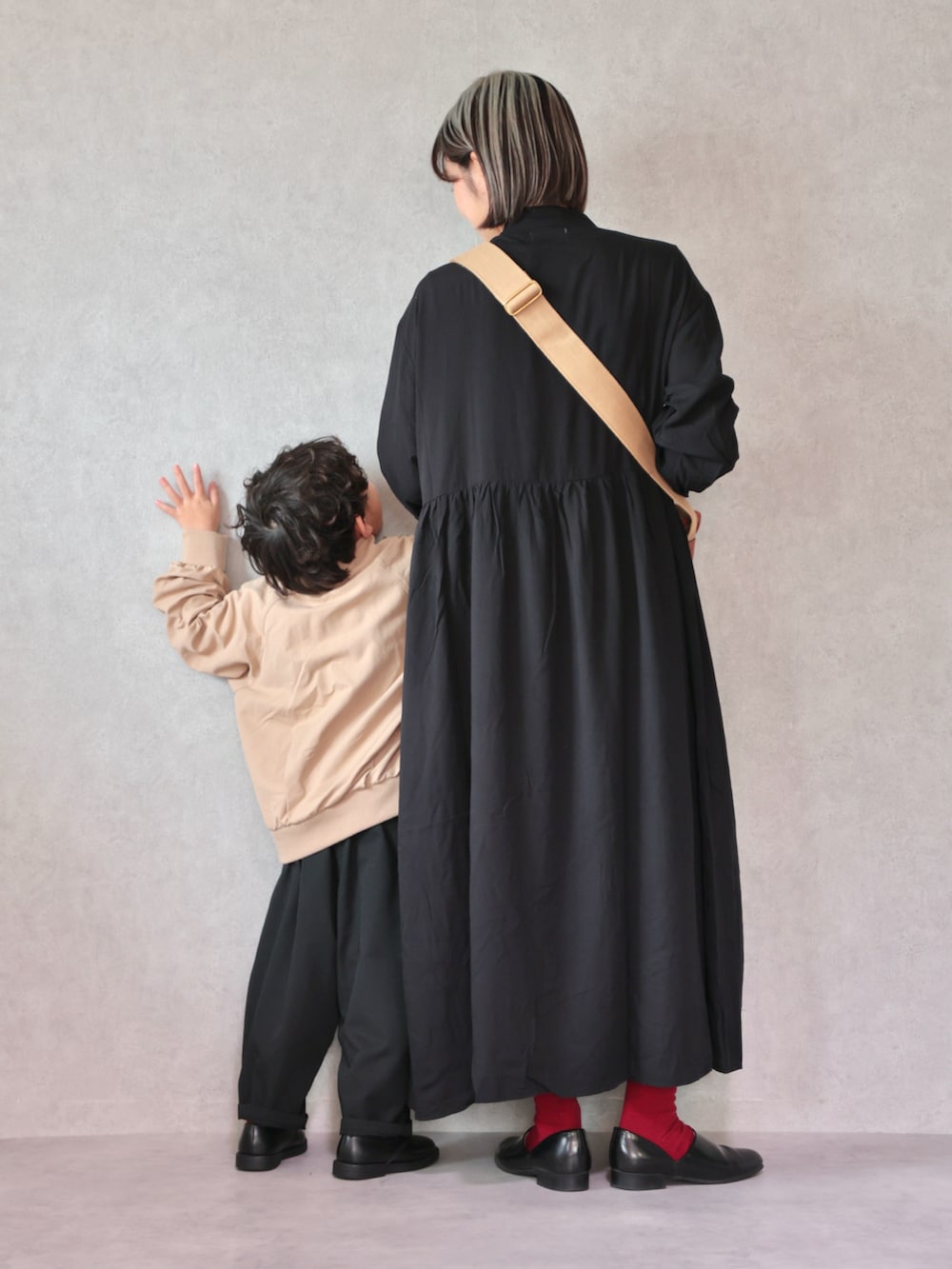 ベージュ系のトレンチコート、ブラック系のワンピース、ブラック系のドレスシューズを着用したキッズの冬コーディネートの4枚目の写真