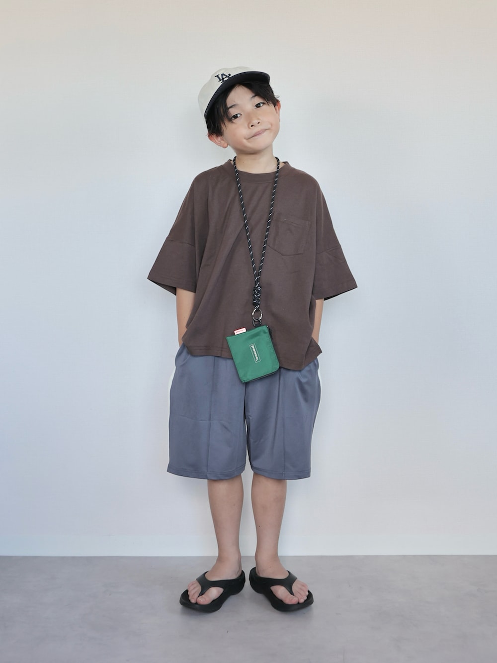ブラウン系のTシャツ/カットソー、ブラック系のサンダル、グレー系のスウェットパンツを着用したキッズの夏コーディネートの4枚目の写真