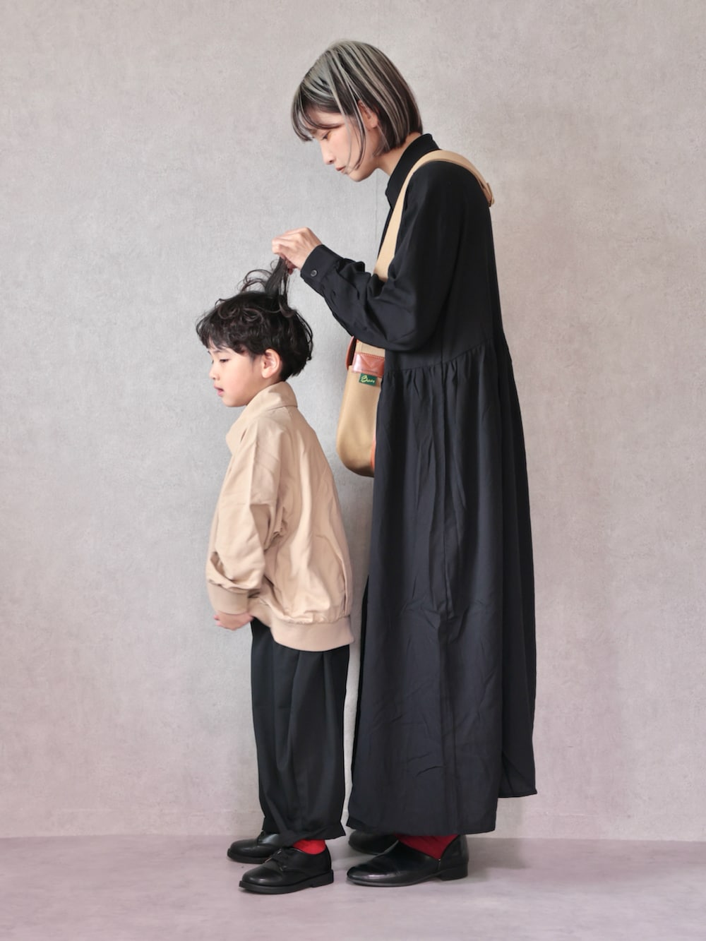 ベージュ系のトレンチコート、ブラック系のワンピース、ブラック系のドレスシューズを着用したキッズの冬コーディネートの3枚目の写真