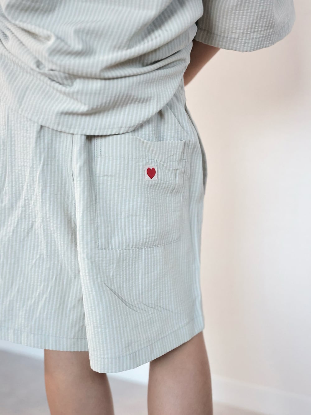 グリーン系のセットアップ、グレー系のスニーカー、ブラウン系のキャップを着用したキッズの夏コーディネートの3枚目の写真