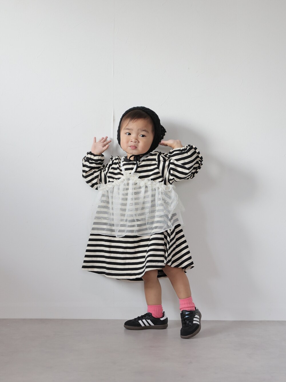 ホワイト系のチュニック、ブラック系のワンピース、ブラック系のスニーカーを着用したキッズの秋コーディネートの2枚目の写真