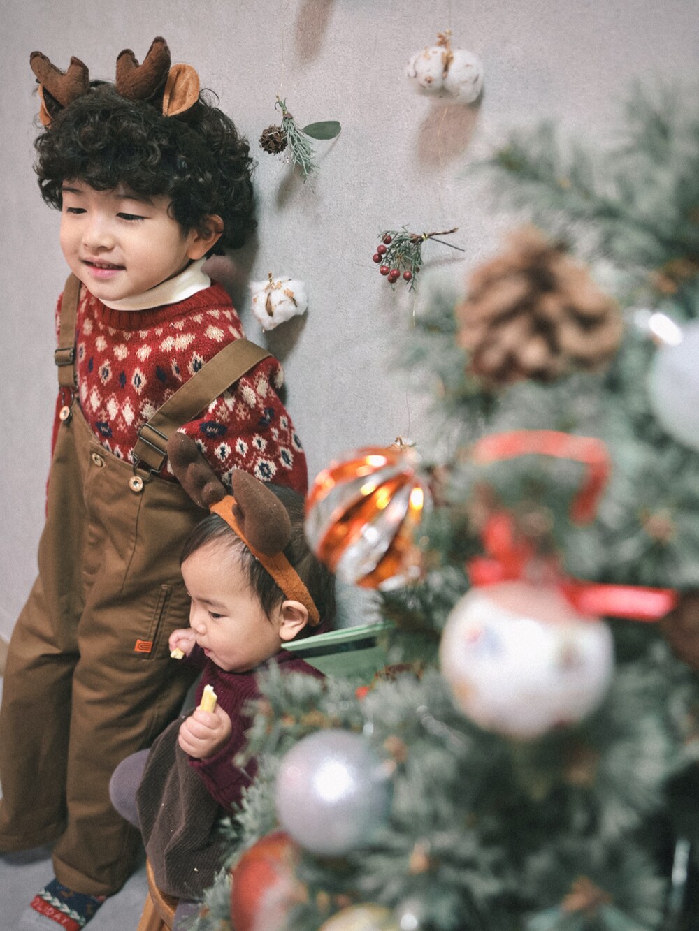 レッド系のニット/セーター、ホワイト系のTシャツ/カットソー、ブラウン系のサロペット/オーバーオールを着用したキッズの冬コーディネートの5枚目の写真