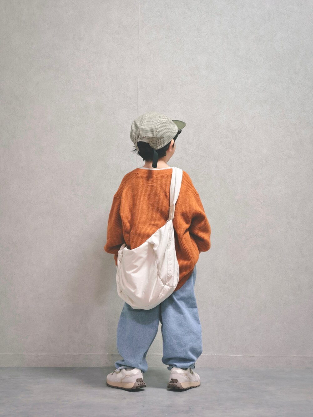 オレンジ系のニット/セーター、ホワイト系のスウェット、ブルー系のデニムパンツを着用したキッズの秋コーディネートの4枚目の写真