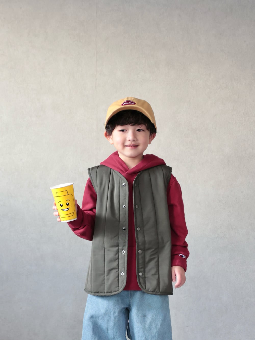 グリーン系のベスト、レッド系のパーカー、ブルー系のデニムパンツを着用したキッズの冬コーディネートの4枚目の写真