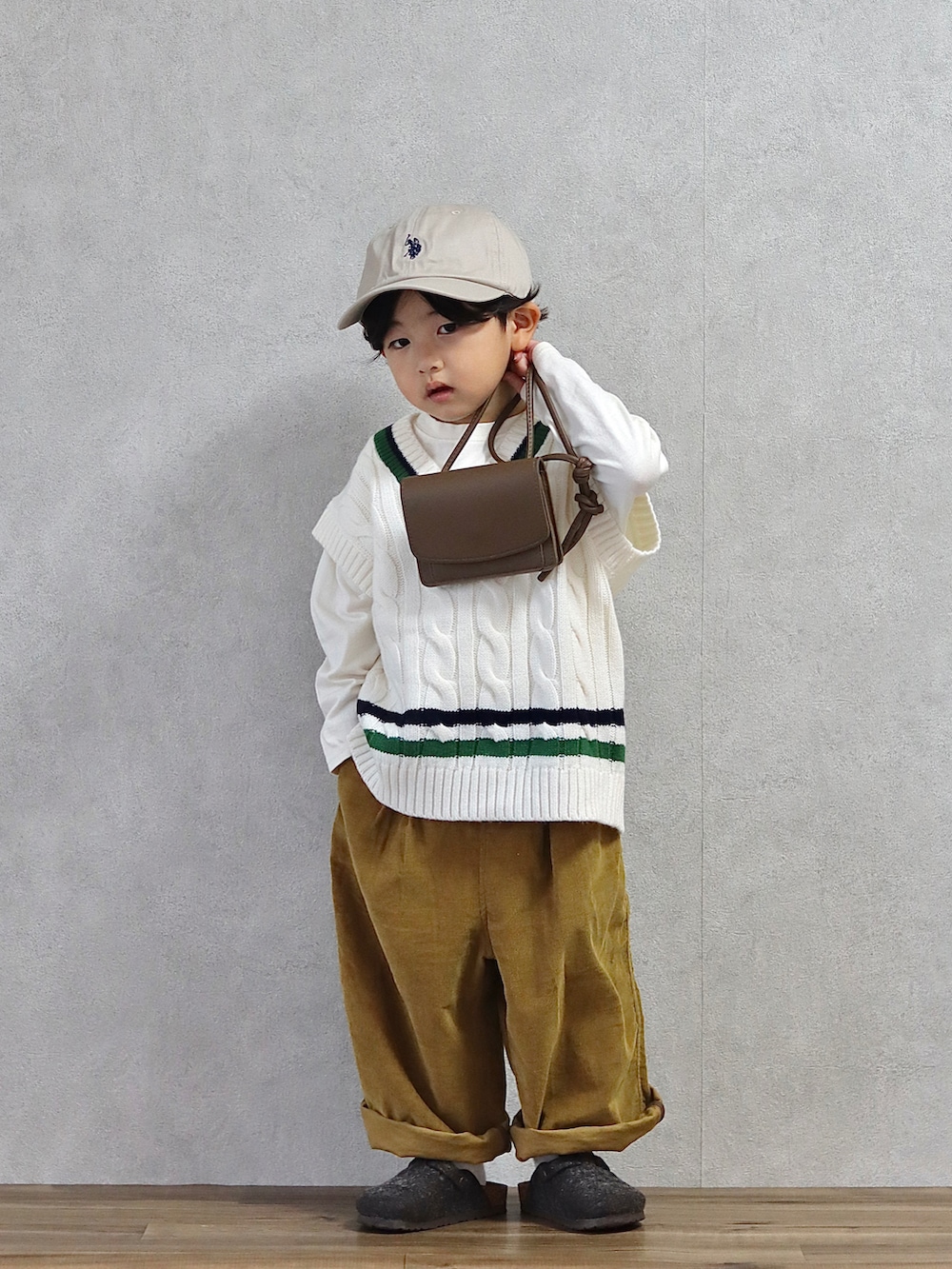 ホワイト系のベスト、ホワイト系のTシャツ/カットソー、ブラウン系のパンツを着用したキッズの秋コーディネートの2枚目の写真