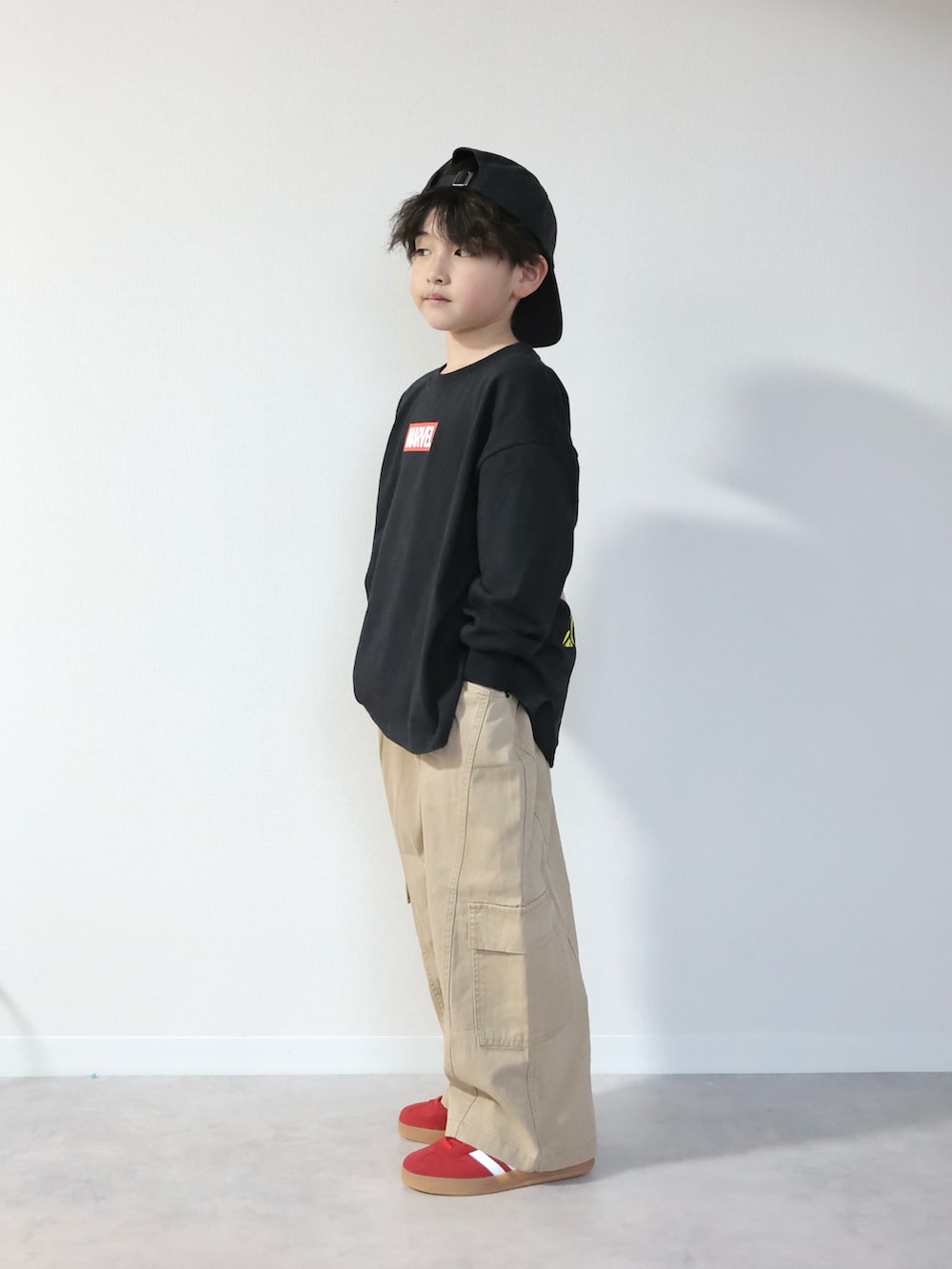 ブラック系のTシャツ/カットソー、ベージュ系のその他パンツ、レッド系のスニーカーを着用したキッズの冬コーディネートの5枚目の写真