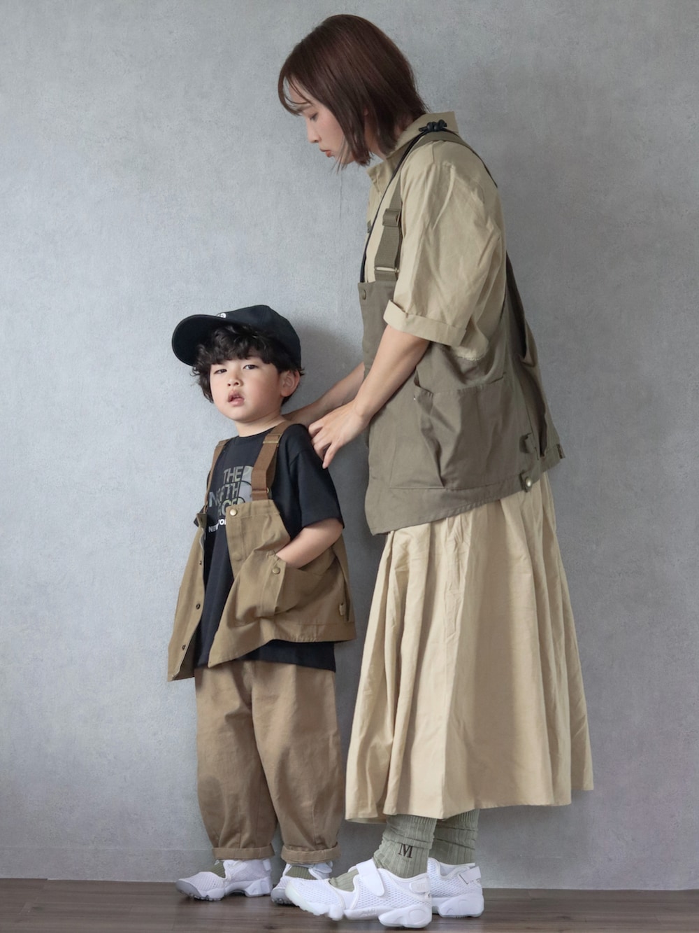 ベージュ系のワンピース、グリーン系のベスト、ホワイト系のスニーカーを着用したキッズの春コーディネートの3枚目の写真