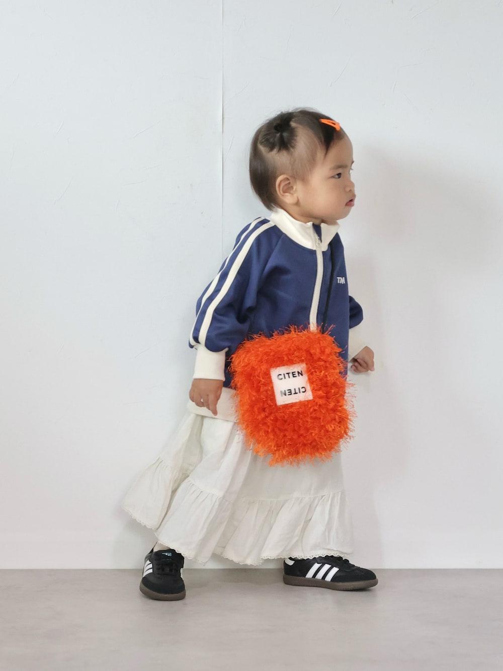 オレンジ系のショルダーバッグ、ブルー系のジャケット/アウター、ホワイト系のスカートを着用したキッズの秋コーディネートの3枚目の写真