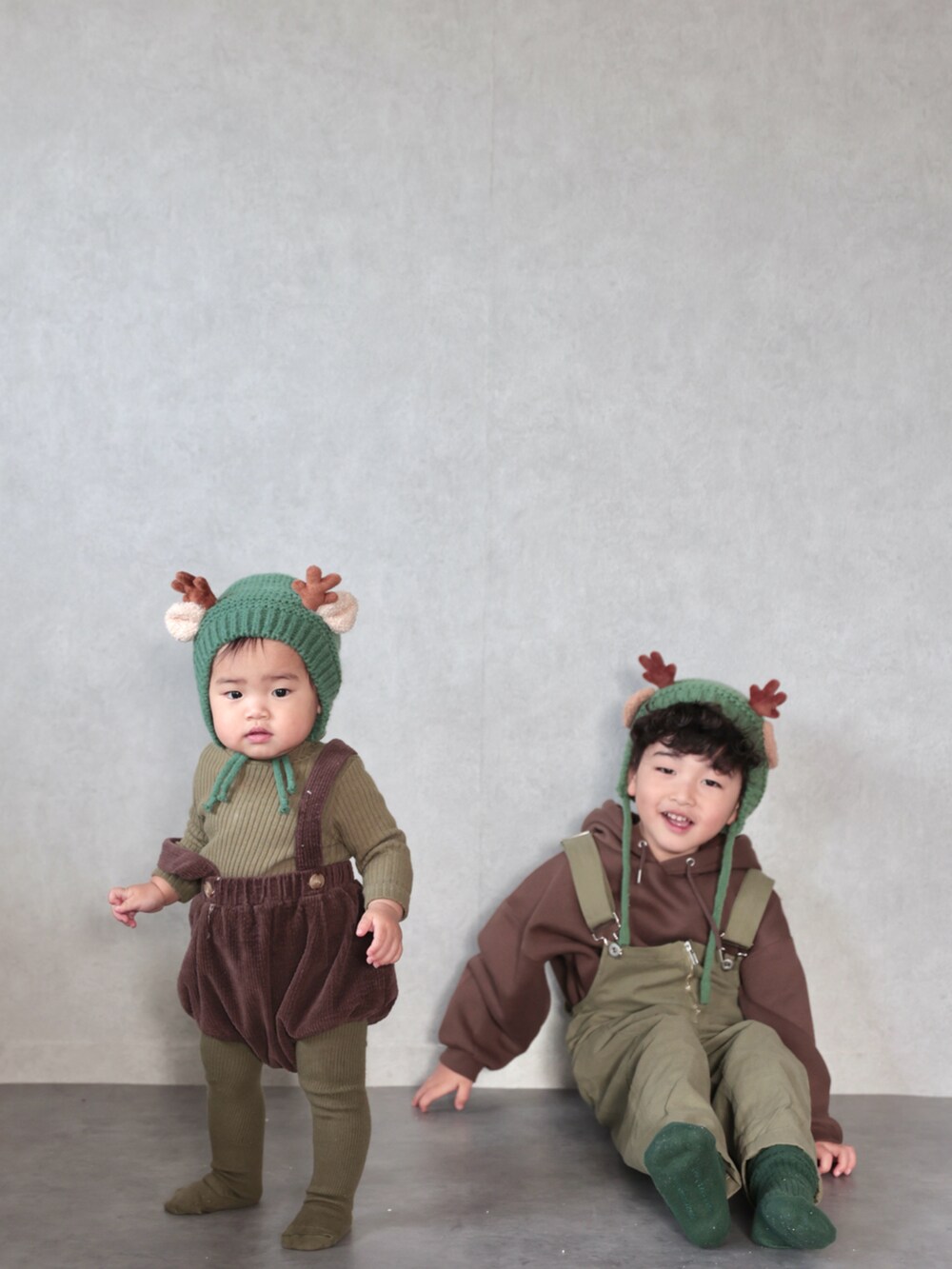 グリーン系のサロペット/オーバーオール、ブラウン系のパーカー、グリーン系のソックス/靴下を着用したキッズの冬コーディネートの4枚目の写真