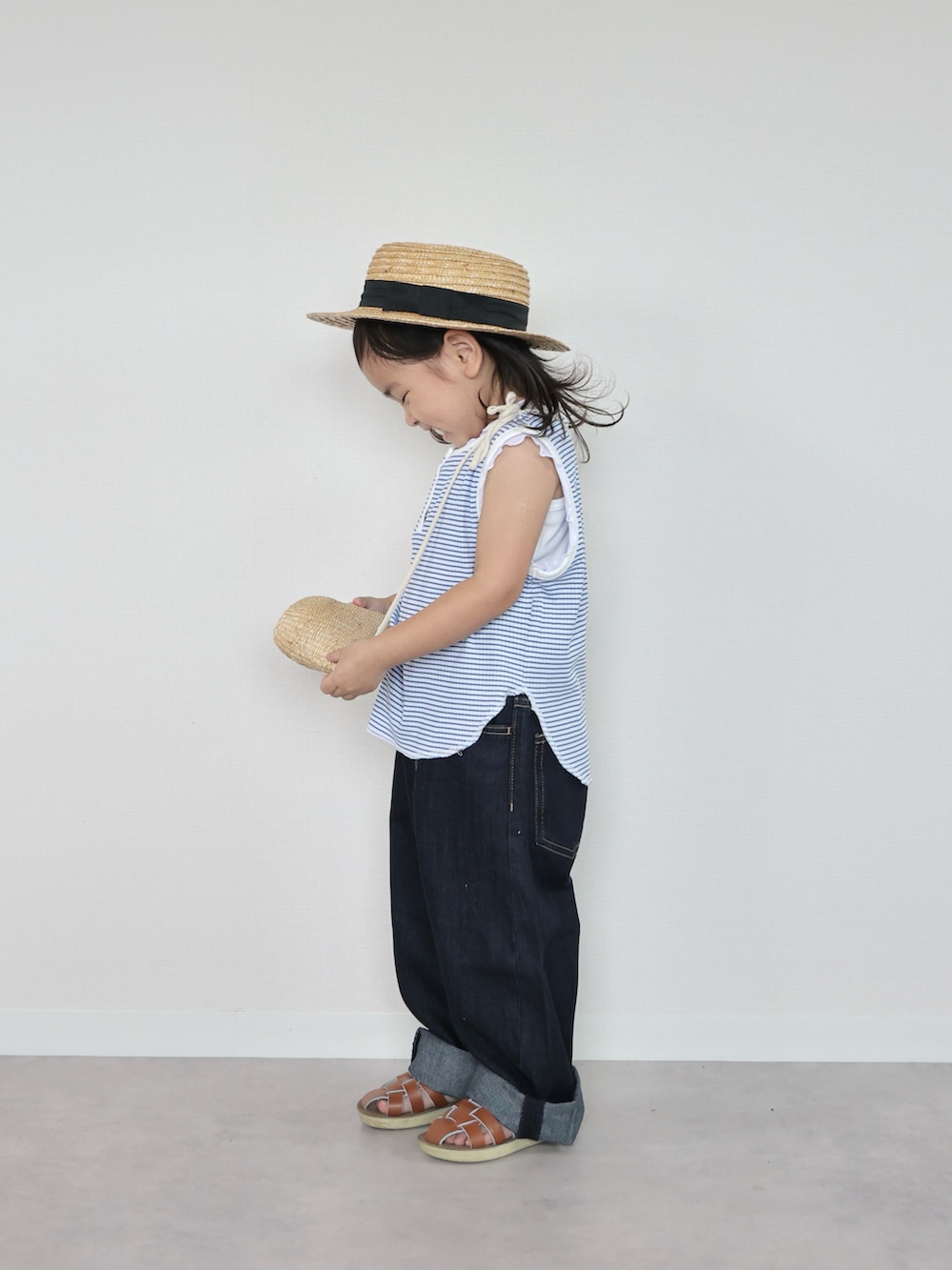 ブルー系のタンクトップ、ブラウン系のサンダル、ベージュ系のショルダーバッグを着用したキッズの夏コーディネートの2枚目の写真