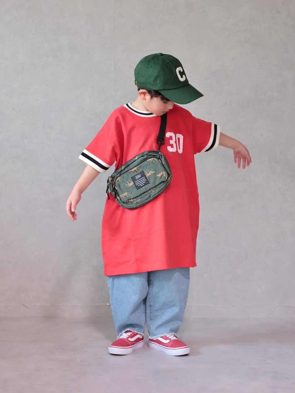 レッド系のワンピース、ブルー系のデニムパンツ、レッド系のスニーカーを着用したキッズの春コーディネートの2枚目の写真