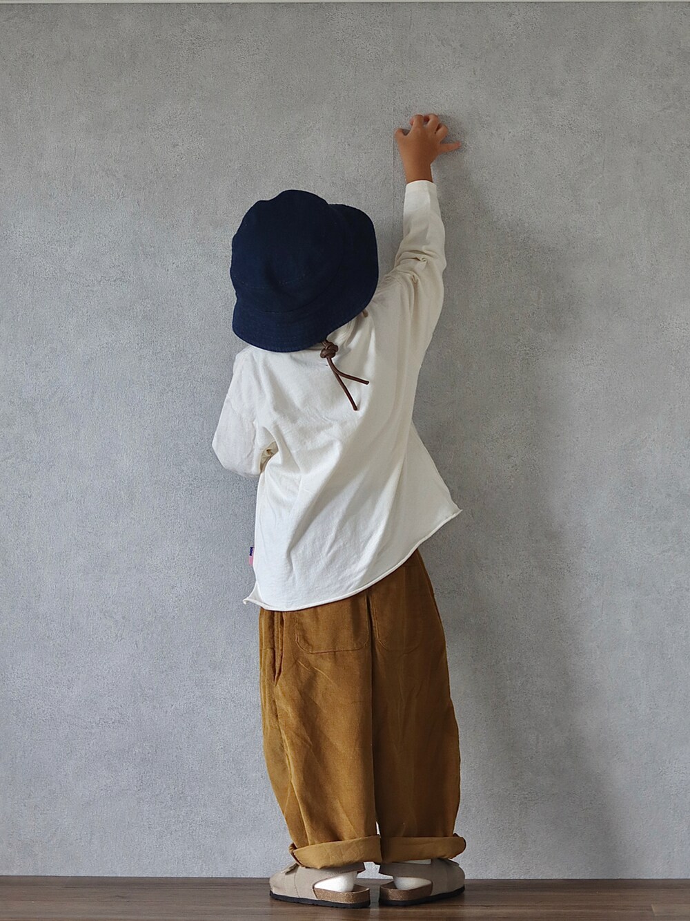 ホワイト系のTシャツ/カットソー、ブラウン系のパンツ、ベージュ系のサンダルを着用したキッズの秋コーディネートの3枚目の写真