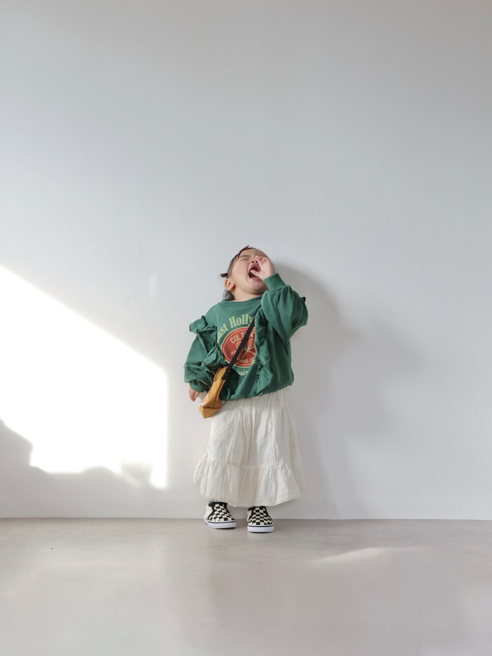 グリーン系のスウェット、ホワイト系のスカート、ブラウン系のショルダーバッグを着用したキッズの冬コーディネートの5枚目の写真