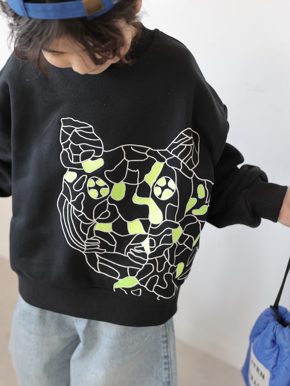 ブラック系のスウェット、ブルー系のデニムパンツ、ブラック系のスニーカーを着用したキッズの冬コーディネートの4枚目の写真