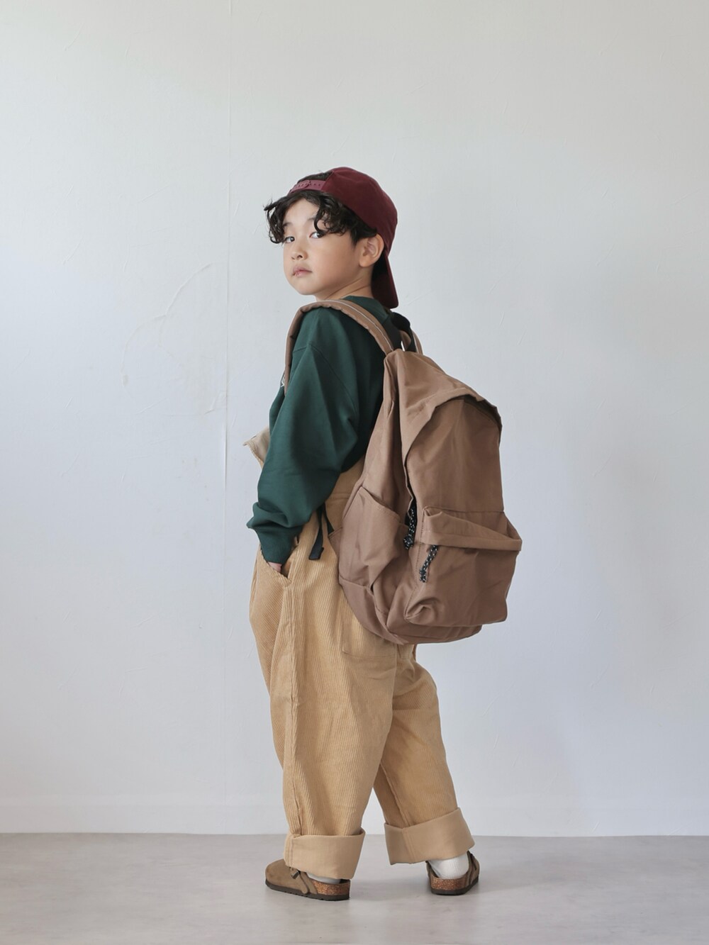 グリーン系のトップス、イエロー系のサロペット/オーバーオール、ベージュ系のシューズを着用したキッズの秋コーディネートの5枚目の写真