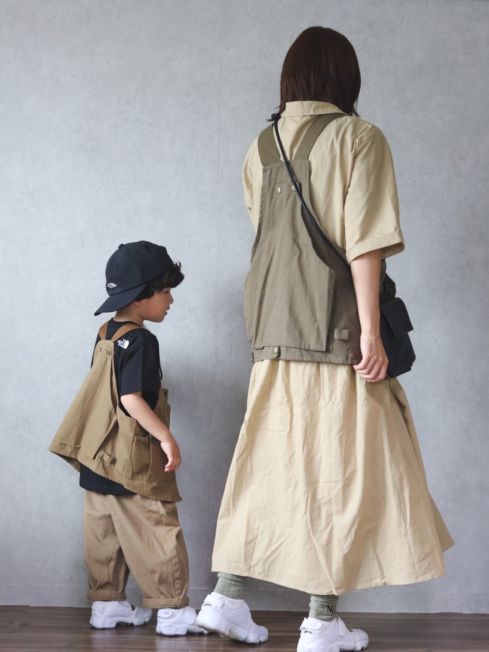 ベージュ系のワンピース、グリーン系のベスト、ホワイト系のスニーカーを着用したキッズの春コーディネートの2枚目の写真