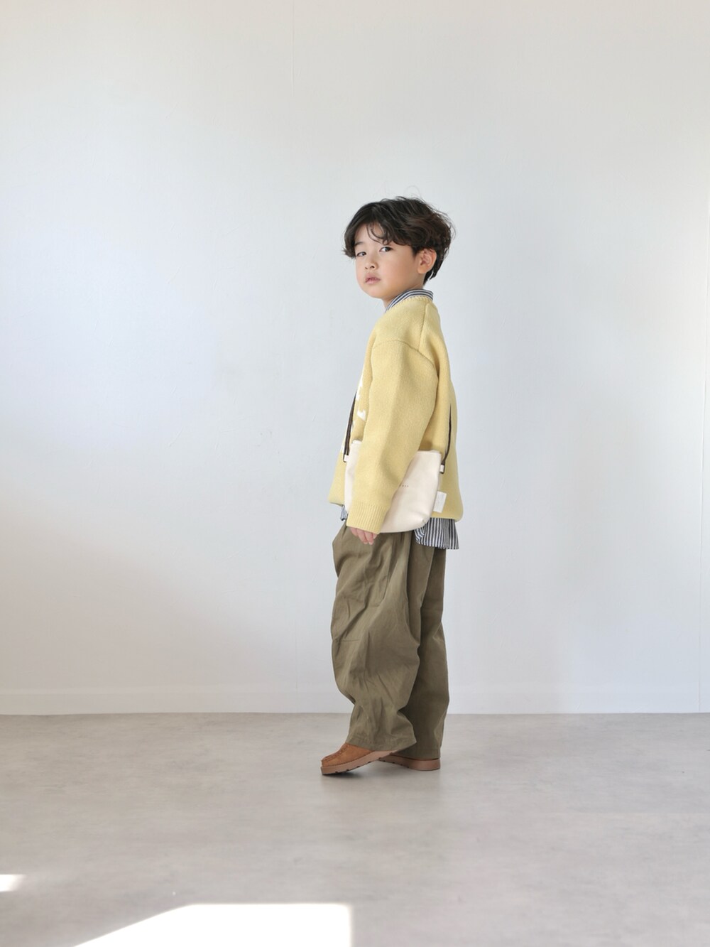 イエロー系のニット/セーター、ブラック系のシャツ/ブラウス、グリーン系のカーゴパンツを着用したキッズの冬コーディネートの3枚目の写真
