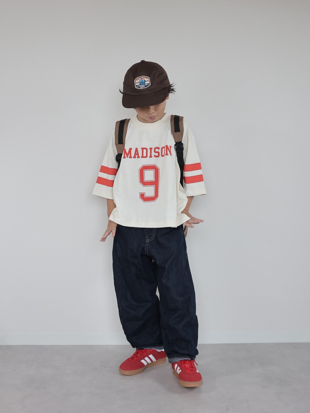 レッド系のスニーカー、ホワイト系のTシャツ/カットソー、ブラウン系のバックパック/リュックを着用したキッズの秋コーディネートの4枚目の写真