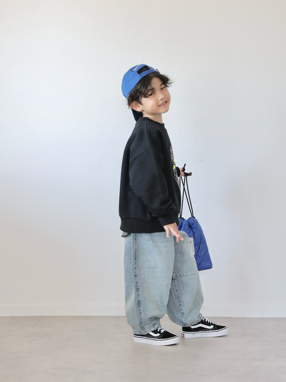 ブラック系のスウェット、ブルー系のデニムパンツ、ブラック系のスニーカーを着用したキッズの冬コーディネートの2枚目の写真