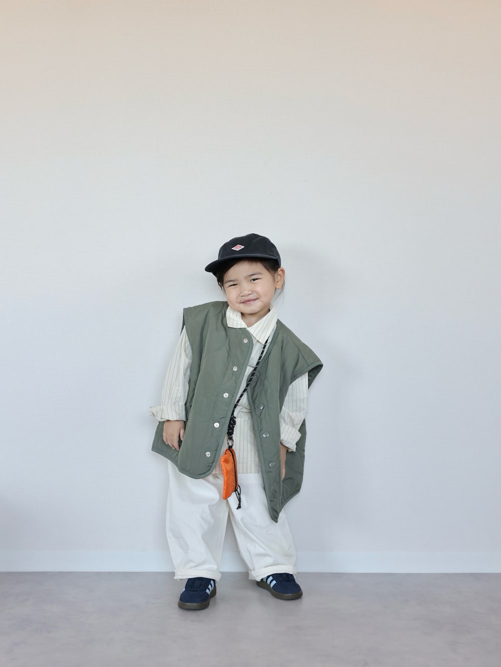 グリーン系のベスト、イエロー系のシャツ/ブラウス、ブルー系のスニーカーを着用したキッズの春コーディネートの5枚目の写真