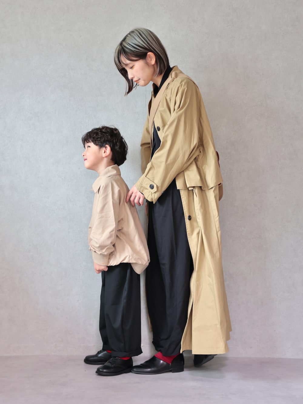 ベージュ系のトレンチコート、ブラック系のワンピース、ブラック系のドレスシューズを着用したキッズの冬コーディネートの5枚目の写真
