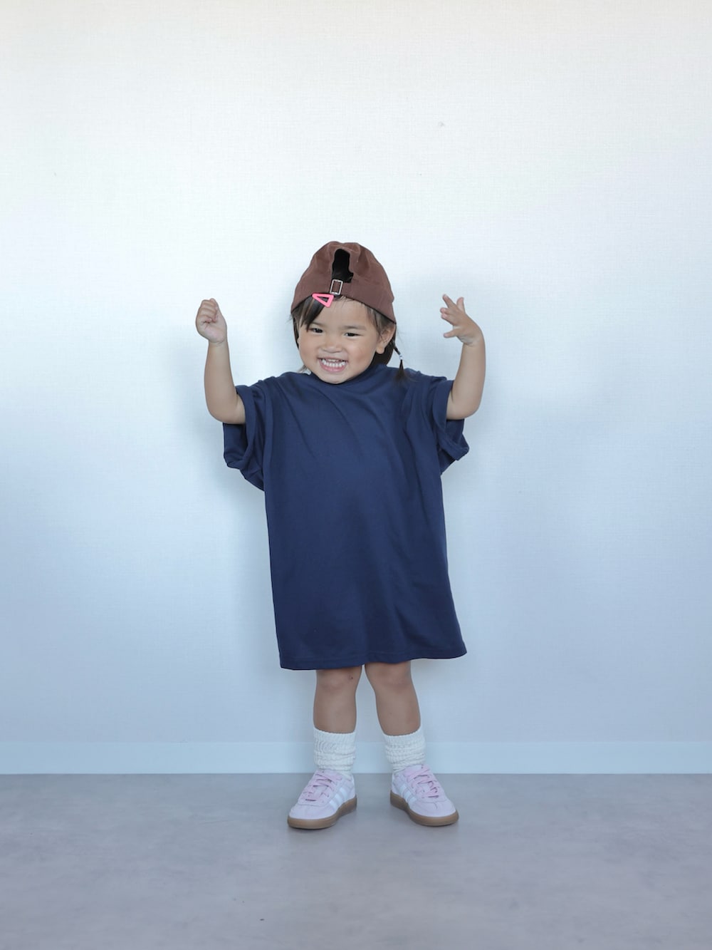 ブルー系のワンピース、ピンク系のスニーカー、ブラウン系のキャップを着用したキッズの夏コーディネートの3枚目の写真