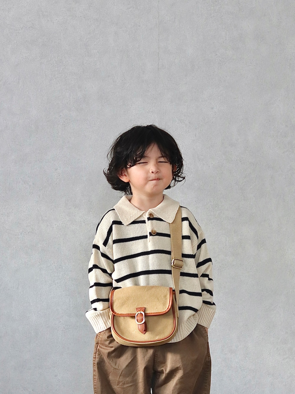 ホワイト系のニット/セーター、ブラウン系のチノパンツ、ブラック系のブーツを着用したキッズの秋コーディネートの4枚目の写真