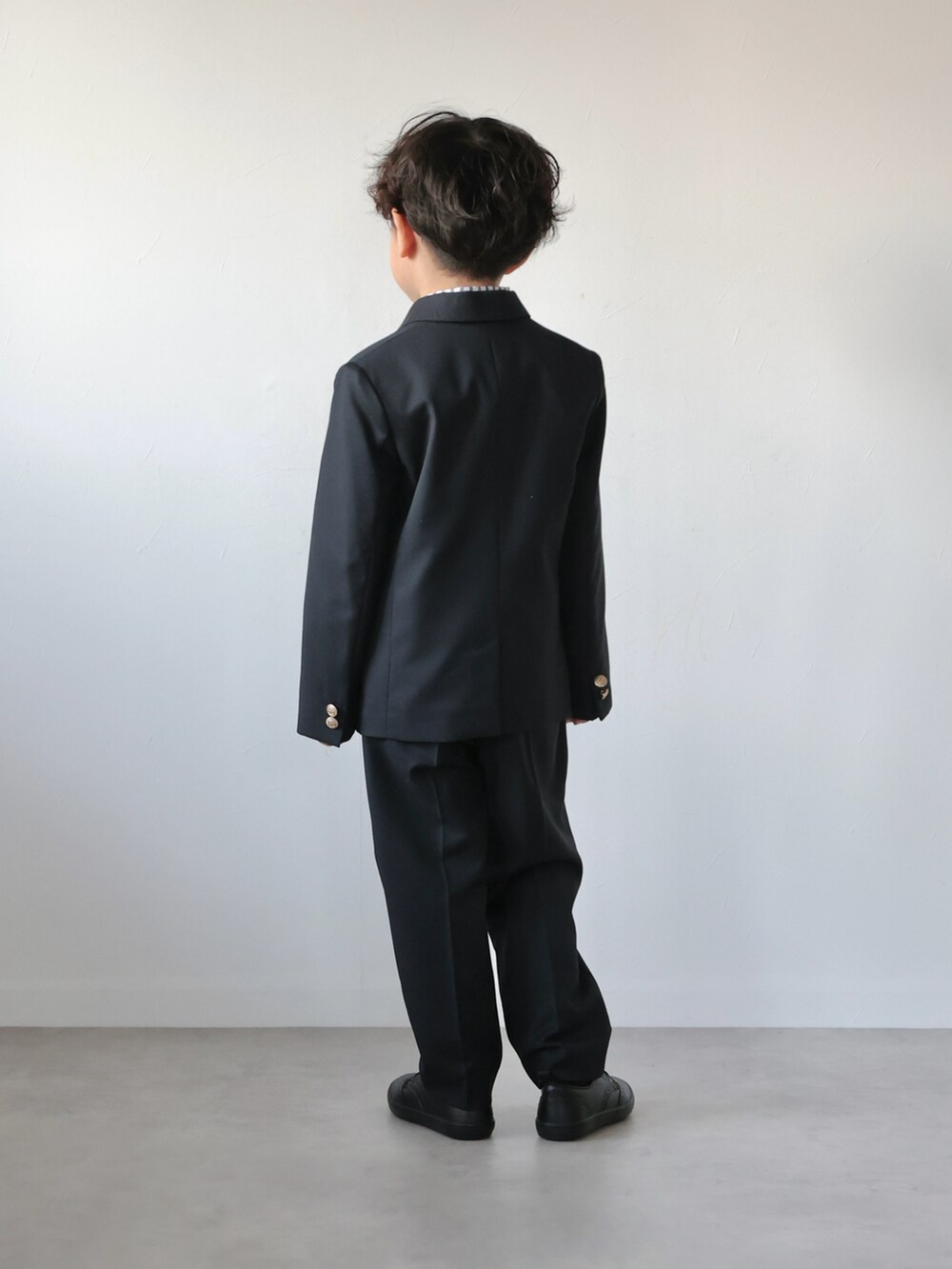 ブルー系のスーツジャケット、ブルー系のスーツパンツ、グリーン系の蝶ネクタイを着用したキッズの冬コーディネートの4枚目の写真