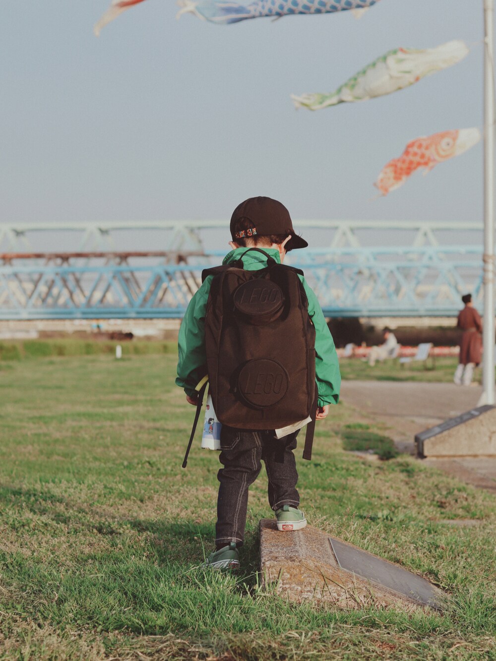 グリーン系のブルゾン、ブルー系のデニムパンツ、グリーン系のスニーカーを着用したキッズの春コーディネートの2枚目の写真