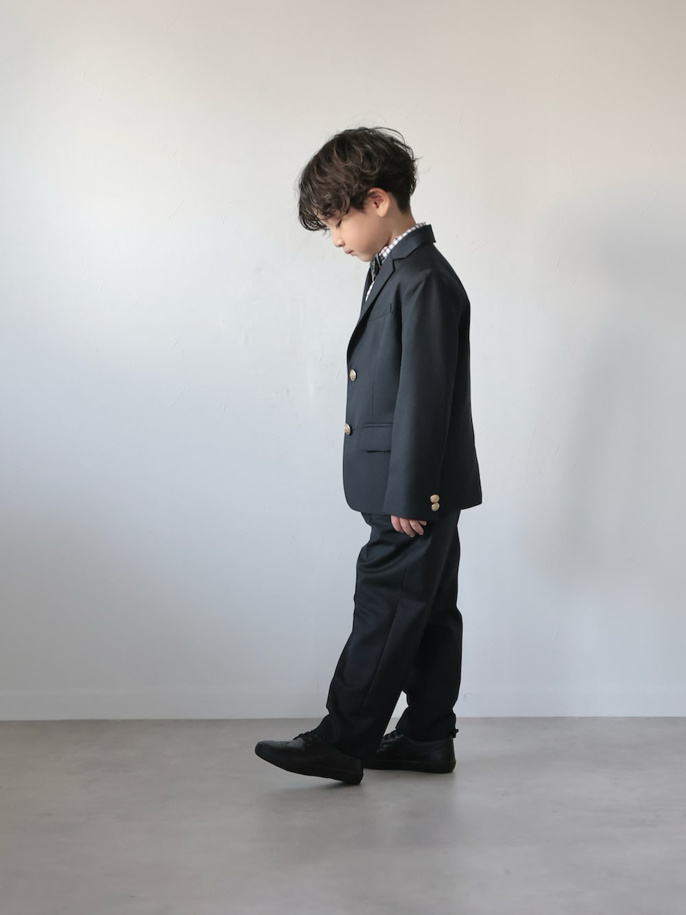 ブルー系のスーツジャケット、ブルー系のスーツパンツ、グリーン系の蝶ネクタイを着用したキッズの冬コーディネートの2枚目の写真