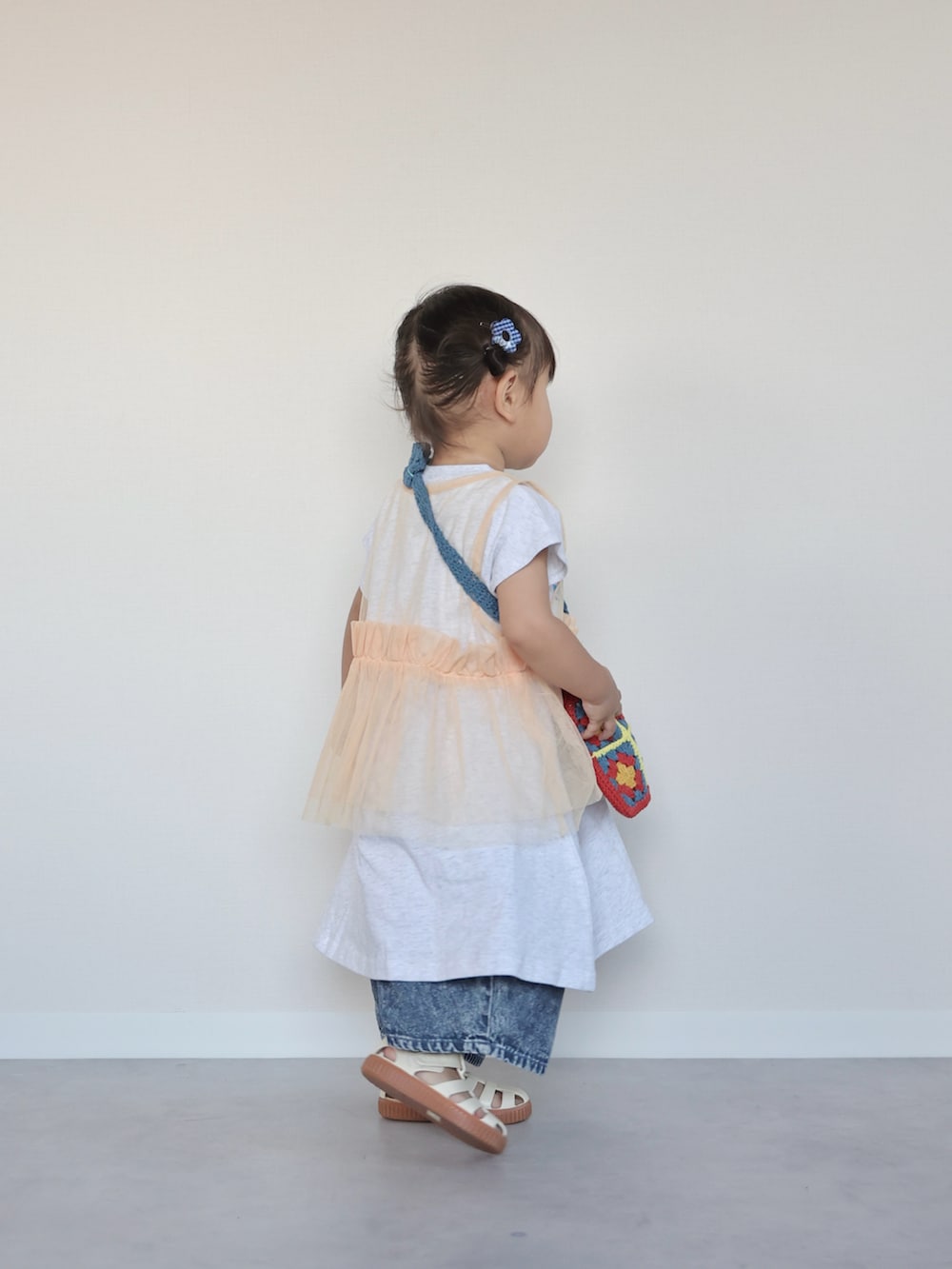ホワイト系のワンピース、ブルー系のデニムパンツ、ホワイト系のサンダルを着用したキッズの夏コーディネートの2枚目の写真