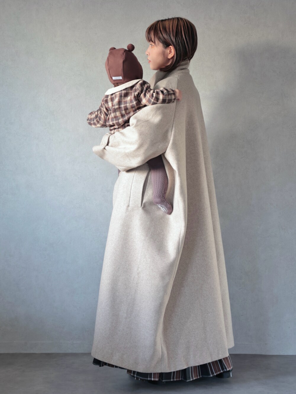 ベージュ系のその他アウター、ホワイト系のニット/セーター、ブラウン系のスカートを着用したキッズの秋コーディネートの4枚目の写真