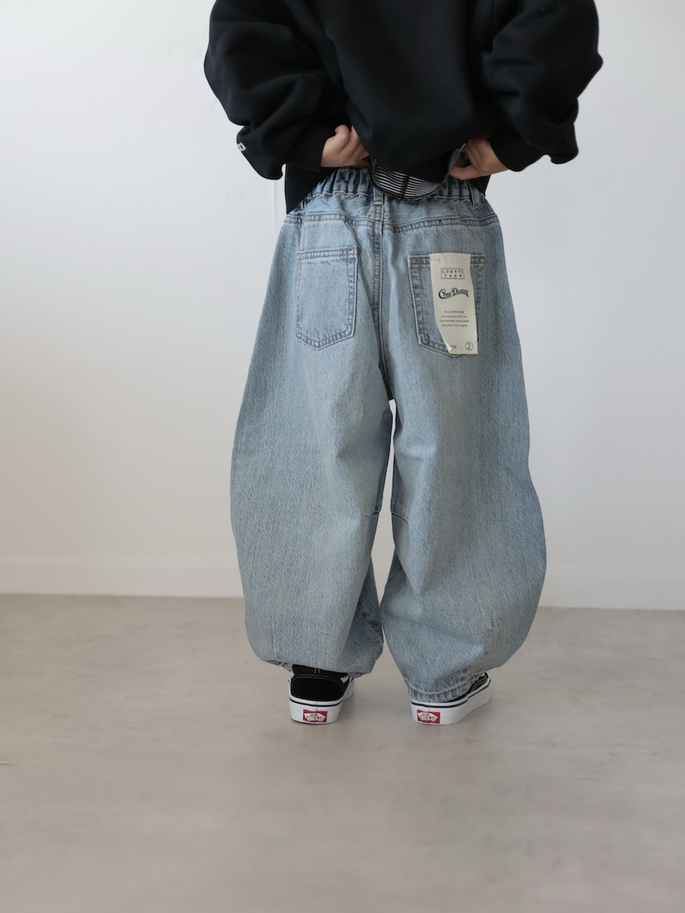 ブラック系のスウェット、ブルー系のデニムパンツ、ブラック系のスニーカーを着用したキッズの冬コーディネートの3枚目の写真