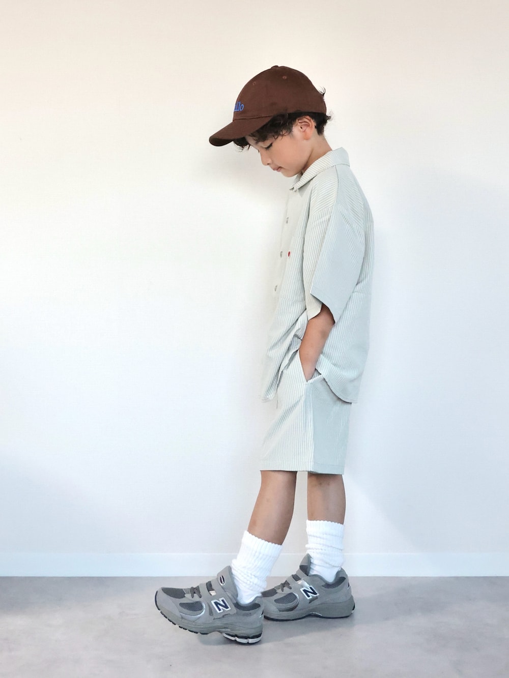 グリーン系のセットアップ、グレー系のスニーカー、ブラウン系のキャップを着用したキッズの夏コーディネートの2枚目の写真