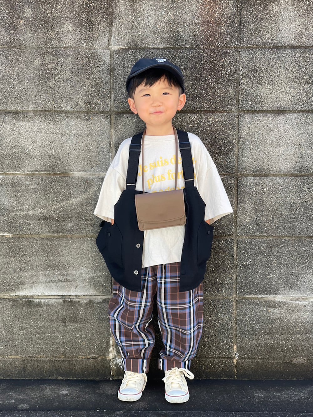 ホワイト系のTシャツ/カットソー、ブラック系のベスト、ブラウン系のパンツを着用したキッズの秋コーディネートの2枚目の写真